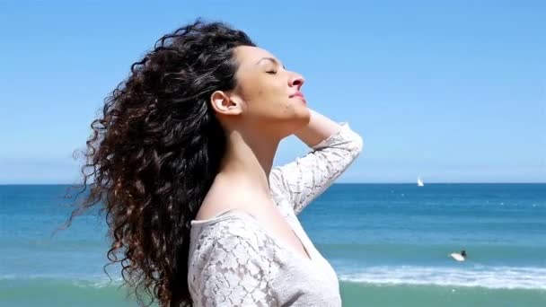 Portrait de jeune femme heureuse avec de beaux cheveux bouclés sur le bord de la mer, au ralenti — Video