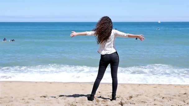 Movimiento lento de la joven feliz con hermoso pelo rizado disfrutando del sol de verano en la orilla del mar — Vídeo de stock