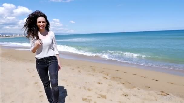 Ευτυχισμένη νεαρή γυναίκα με όμορφα σγουρά μαλλιά περπάτημα στη θάλασσα παραλία, αργή κίνηση — Αρχείο Βίντεο
