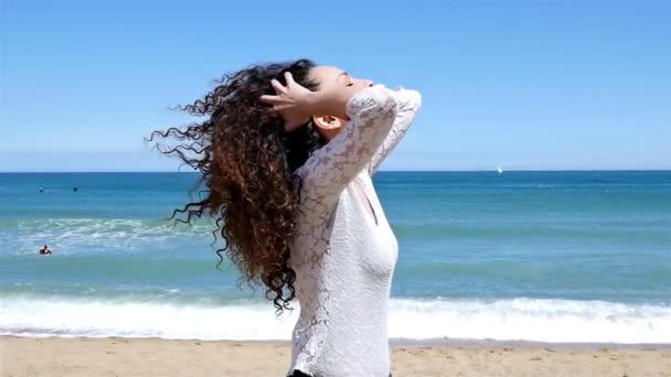 Portrait of happy young woman with beautiful curly hair on the sea shore, slow motion — Stock Video