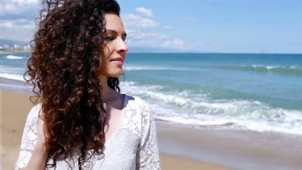 Portrait de jeune femme heureuse avec de beaux cheveux bouclés sur le bord de la mer, au ralenti — Video