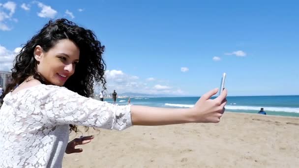 Портрет красивой молодой женщины, делающей селфи со смартфоном на пляже, замедленная съемка — стоковое видео