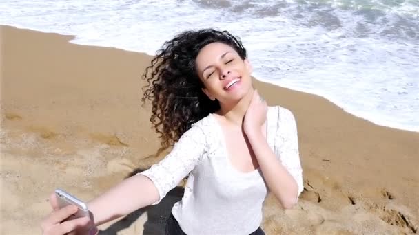 Retrato de una hermosa joven tomando selfie con un teléfono inteligente en la playa, cámara lenta — Vídeos de Stock