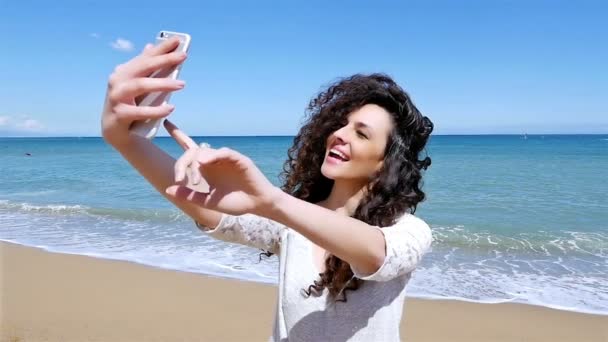 Retrato de una hermosa joven tomando selfie con un teléfono inteligente en la playa, cámara lenta — Vídeos de Stock