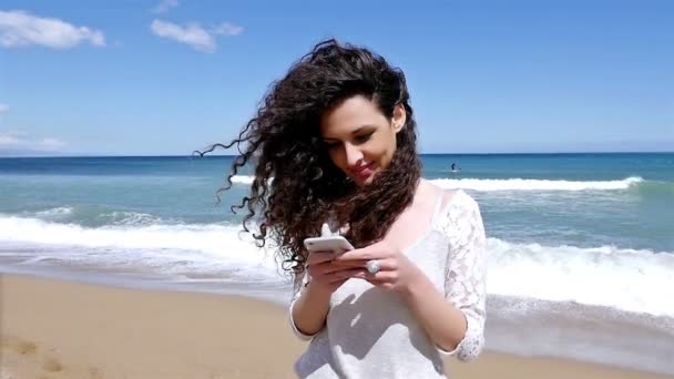 Mujer bastante joven con teléfono inteligente en la playa del mar, cámara lenta — Vídeo de stock