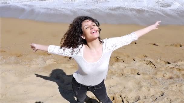 Медленное движение счастливой молодой женщины с красивыми вьющимися волосами наслаждаясь летним солнцем на берегу моря, снимок под низким углом — стоковое видео