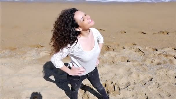 Slow Motion van gelukkige jonge vrouw met mooie krullend haar genieten van de zomerzon aan de kust, lage hoek schot — Stockvideo