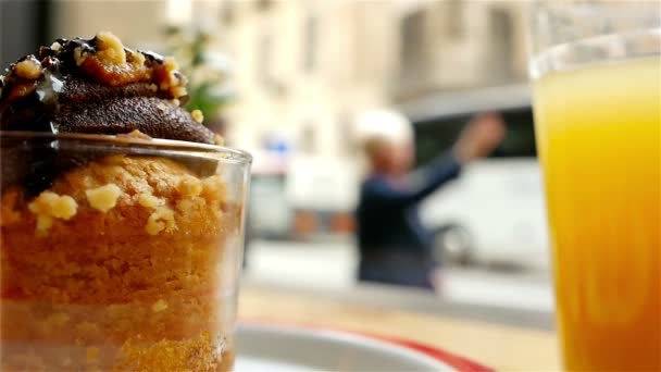 Persone e traffico dietro finestre di un caffè, un muffin e un succo di frutta di fronte — Video Stock