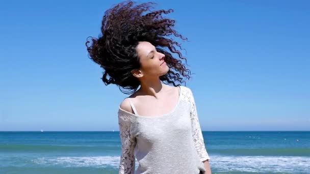바다 해안에 그녀의 아름다운 곱슬 머리를 흔들어 행복한 젊은 여자의 초상화, 슬로우 모션 — 비디오