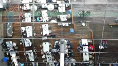 Barcelona'da Maremagnum alışveriş merkezi önünde masalarda oturan insanlar yansıması