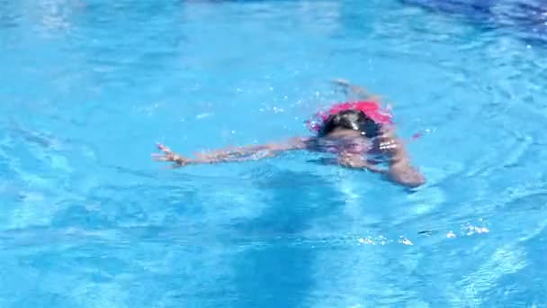 Kleines Mädchen mit Schutzbrille schwimmt unter Wasser im Pool — Stockvideo