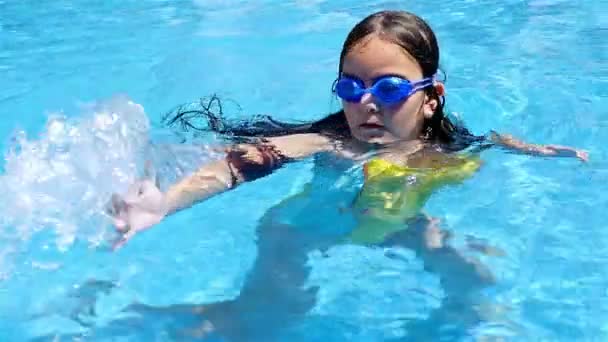 Petite fille en maillot de bain tourbillonnant dans l'eau dans la piscine, au ralenti — Video