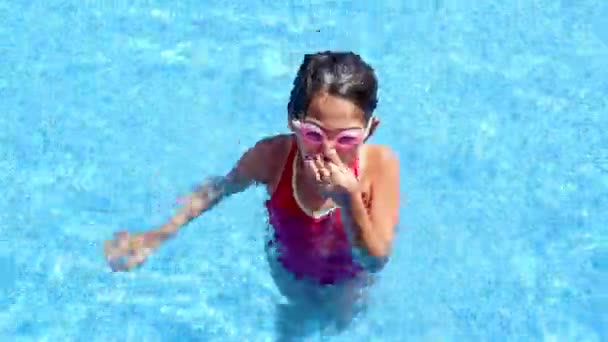 Linda niña metiendo la cabeza en una piscina — Vídeo de stock