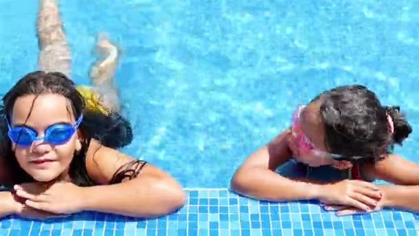 Leuke kleine meisjes met bril glimlachend op de rand van een pool — Stockvideo