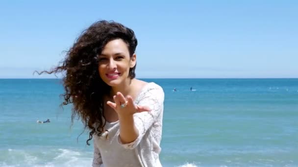 Young woman with beautiful curly hair gesturing follow me and running on the beach — Stock Video