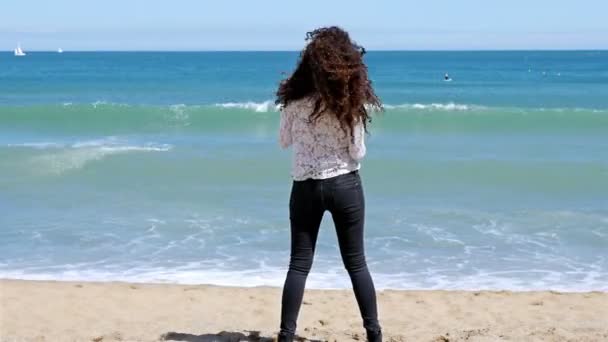 Όμορφη νεαρή γυναίκα τρέχει στην ακτή της θάλασσας και απολαμβάνοντας τον ήλιο του καλοκαιριού — Αρχείο Βίντεο