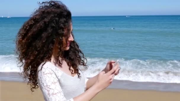 Segítségével okos telefon, a tenger partján, csinos, fiatal nő portréja — Stock videók