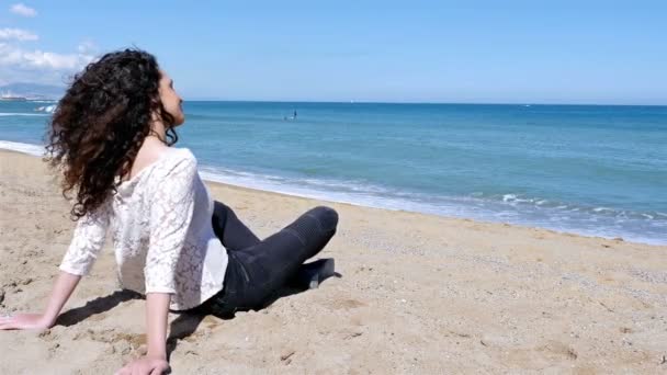 Счастливая молодая женщина с красивыми вьющимися волосами наслаждается летним солнцем на берегу моря — стоковое видео