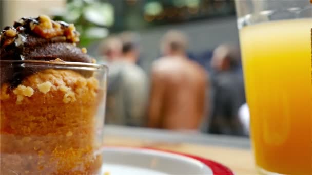 Desfocado pessoas e tráfego da cidade atrás das janelas de um café, muffin e suco na frente — Vídeo de Stock