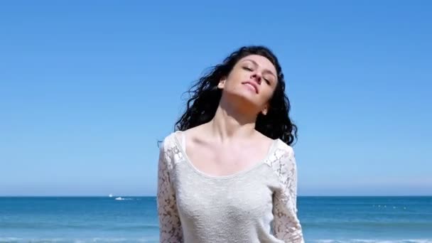Retrato de una joven feliz sacudiendo su hermoso cabello rizado contra el cielo azul — Vídeo de stock