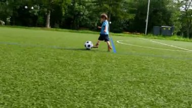 Küçük bir çocuk futbol sahası içinde topa tekme kamera izleme