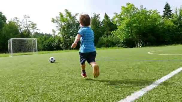 Rastreando câmera de um menino chutando bola no campo de futebol — Vídeo de Stock