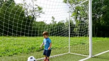Küçük bir çocuk futbol sahası içinde topa tekme kamera izleme