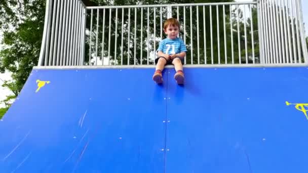 Malý kluk hraje na bruslení rampu na hřišti — Stock video