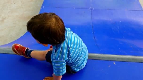 Petit garçon jouant sur une rampe de patinage dans une aire de jeux — Video