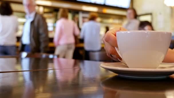 Defokussierte Menschen in einer Höhle, vor sich eine Tasse Kaffee — Stockvideo