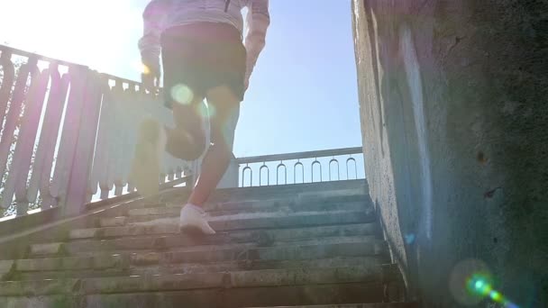 Muž, běhání do slunné schodů. Odlesk objektivu. Detailní záběr — Stock video