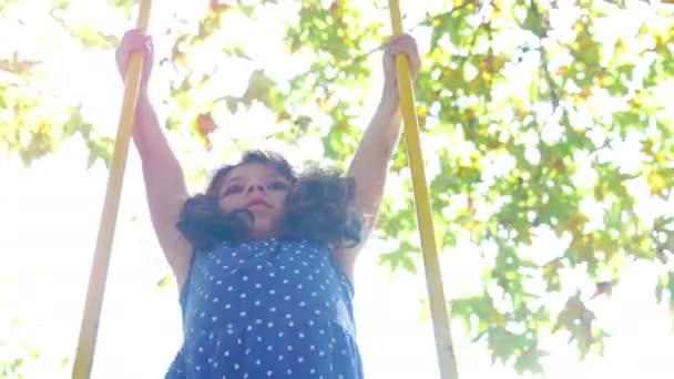 Menina bonito balançando em um parque, erupção solar — Vídeo de Stock