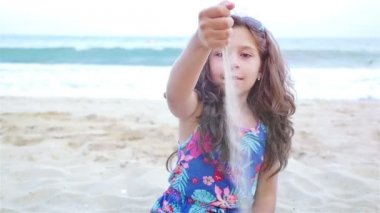 Plajda, yavaş hareket şirin küçük kız dökülen kum yakın çekim