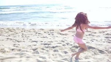 Yavaş çalışan ve deniz sahilde oynarken mayo, sevimli küçük bir kız