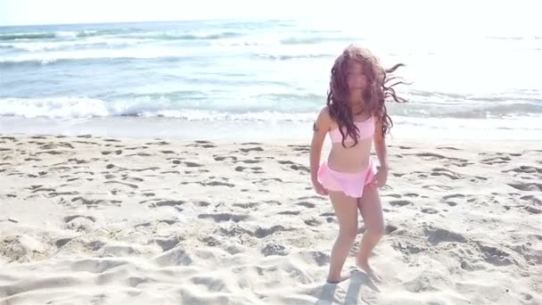 Slow motion of a cute little girl in swimsuit running and playing at the sea beach — Stock Video