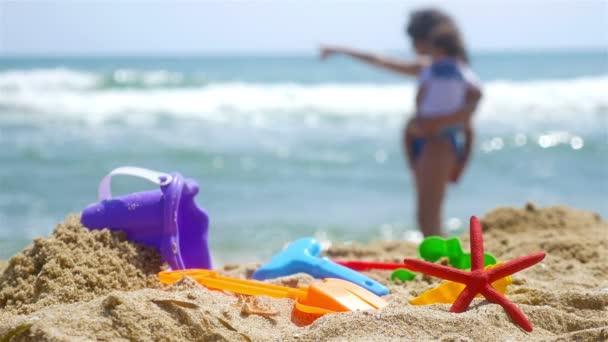 Moeder en kleine zoon spelen op het strand van zee, zand speelgoed vooraan — Stockvideo