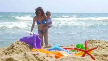 Anne ve küçük oğlu deniz plaj, kum oyuncakları önünde oynarken