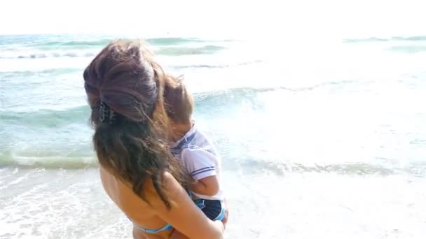 Madre abrazando y besando a su pequeño hijo en la playa del mar — Vídeos de Stock