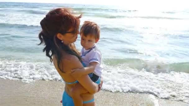 Μητέρα αγκάλιασμα και το φίλημα το μικρό γιο της στην παραλία της θάλασσας — Αρχείο Βίντεο