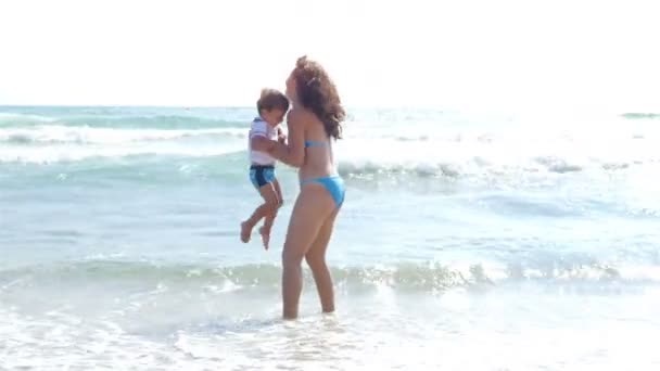 Madre e hijo pequeño jugando con las olas del mar — Vídeos de Stock