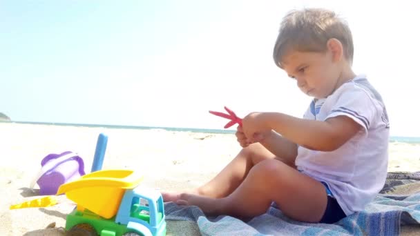 Kleine jongen spelen met zand speelgoed op het zee-strand — Stockvideo