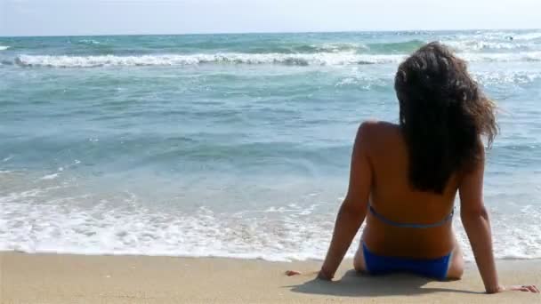 Woman relaxing on the beach, looking at sea water, waves splashing in her body — Stock Video