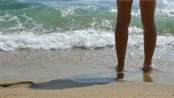 Slow motion van kale vrouwelijke benen op het strand, golven spatten in hen — Stockvideo