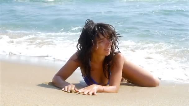 Mulher deitada na areia, as ondas do mar salpicando em seu corpo, câmera lenta — Vídeo de Stock