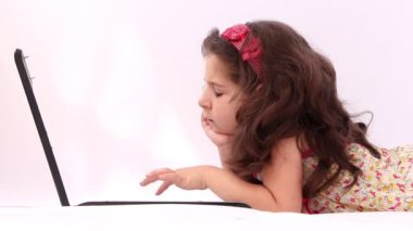 Sevimli kız bir dizüstü bilgisayar, tablet beyaz arka plan ile oynamak