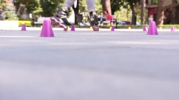 Man en vrouw weven tussen de rij kegels met schaatsen en scooters — Stockvideo