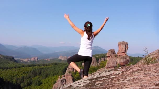 Mujer haciendo ejercicios de yoga en rocas Belogradchik, admirando el valle de Belogradchik — Vídeo de stock