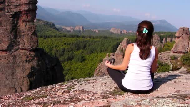 Mulher fazendo exercícios de ioga em rochas Belogradchik, admirando o vale de Belogradchik — Vídeo de Stock