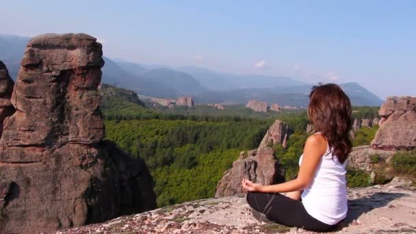 Mujer haciendo ejercicios de yoga en rocas Belogradchik, admirando el valle de Belogradchik — Vídeos de Stock