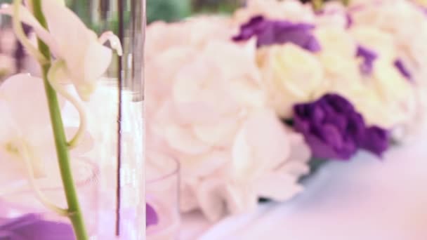Decoración de la boda con flores y velas blancas y moradas — Vídeo de stock